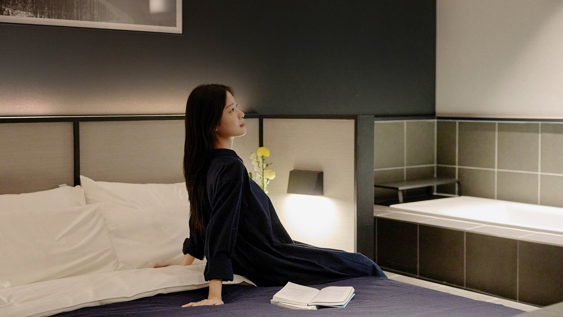 Un dormitorio moderno con una cama, una mesita de noche y otra mesita auxiliar.
