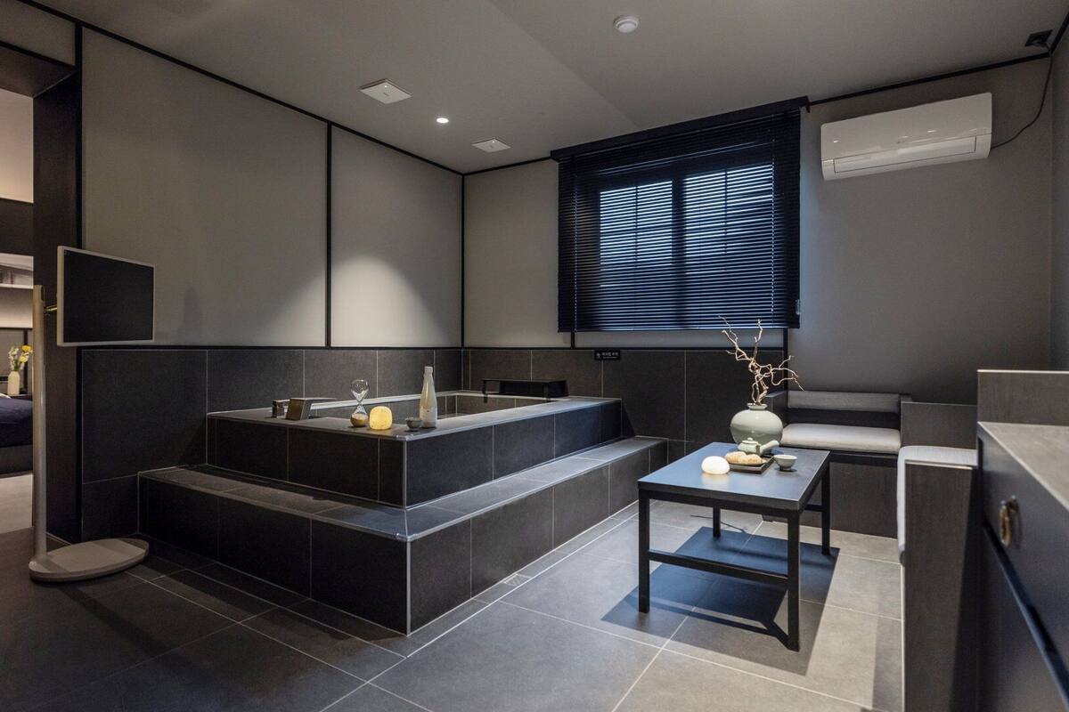 Ein modernes Badezimmer mit einer Badewanne, einem Waschbecken und einem kleinen Tisch mit einer Vase.
