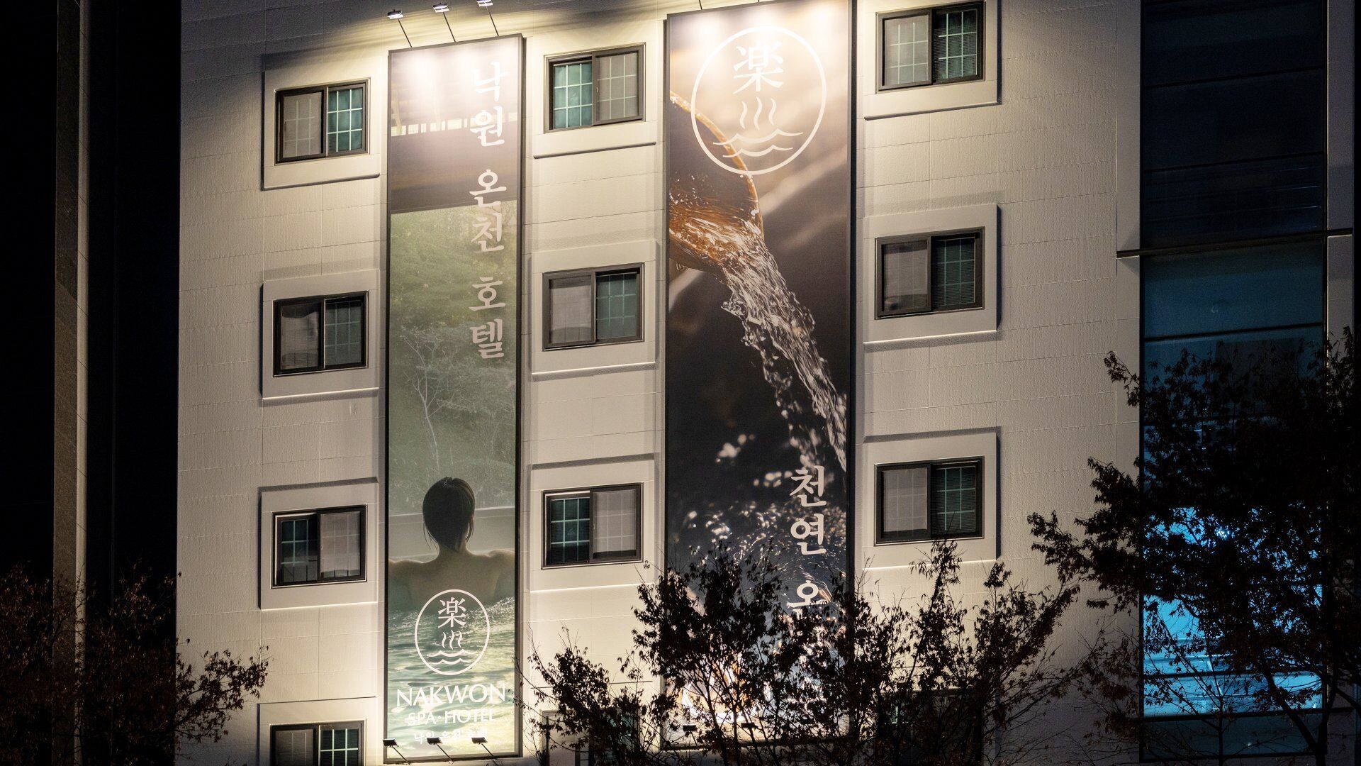 Een gebouw met veel ramen en banners waarop tekst en een logo staan.
