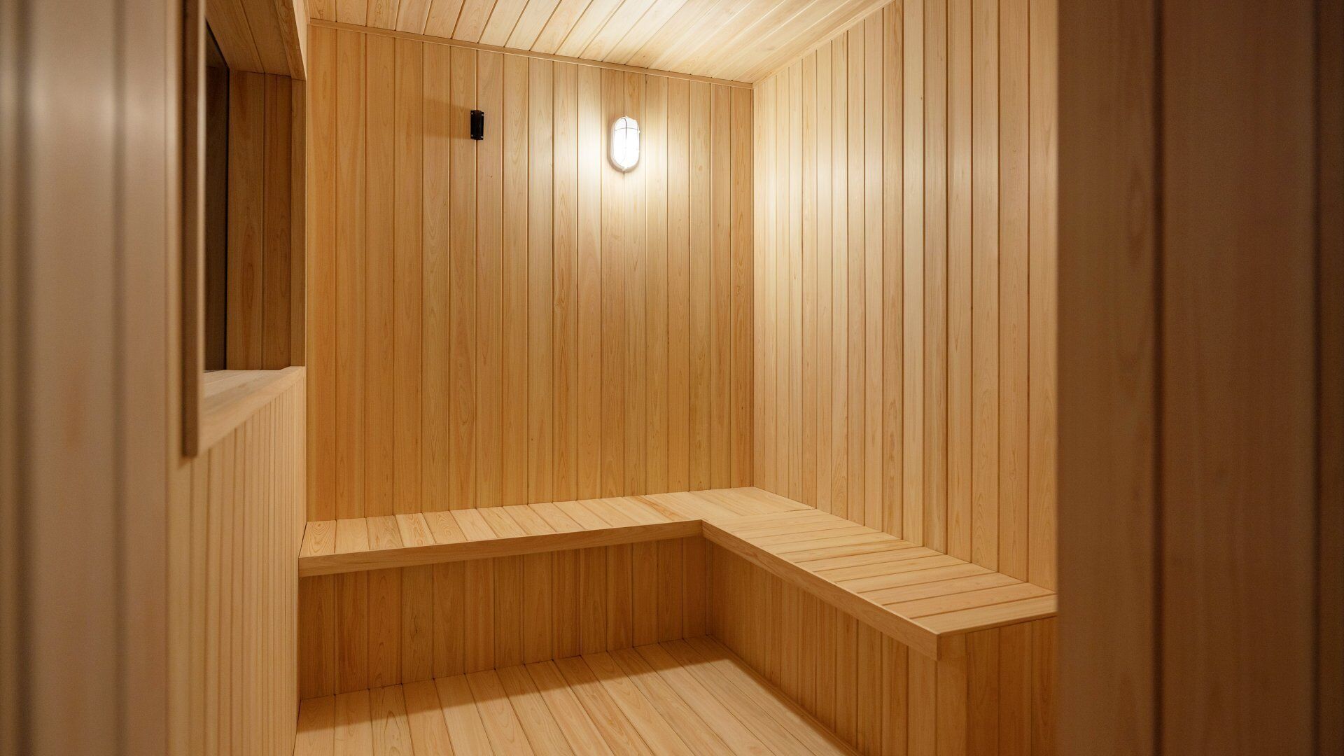 A wooden sauna with a bench and a light fixture.