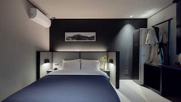 A modern hotel room with a large bed, bedside tables, a mounted artwork, a wardrobe, and a built-in shower.