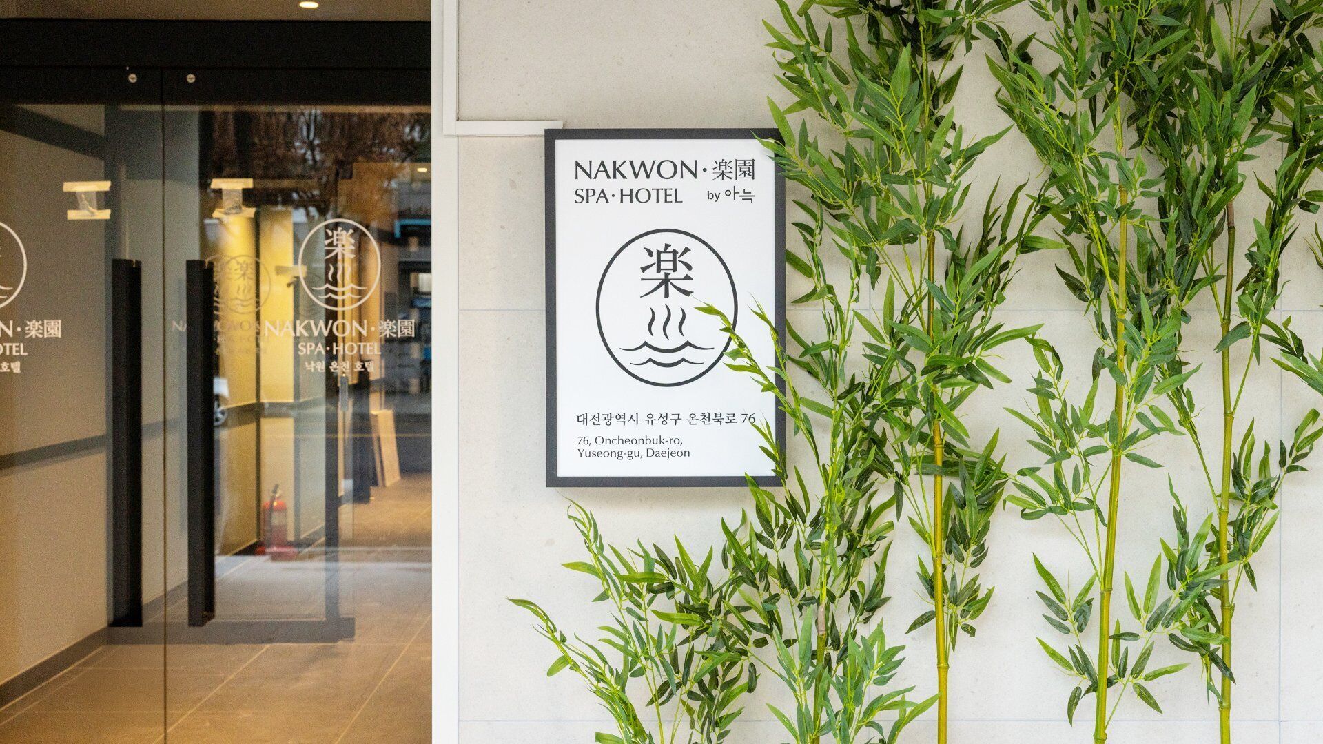 Letrero del Hotel Nakwon Spa con un arreglo de plantas de bambú.