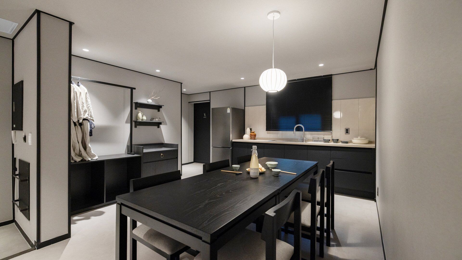 Una cocina moderna con una mesa de comedor, sillas y una lámpara colgante.