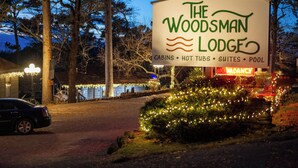 A sign for The Woodsman Lodge with amenities including cabins, hot tubs, suites, and a pool. - Hot Tub- Newly Renovated Cabin. Modern Rustic (Eureka Springs)