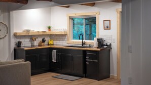 A modern kitchen with black cabinetry, a wooden countertop, and a window with a view of trees. - Hot Tub- Newly Renovated Cabin. Modern Rustic (Eureka Springs)