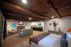 Um quarto espaçoso com uma cama grande, um canto de estar acolhedor, uma cozinha e uma lareira de pedra.