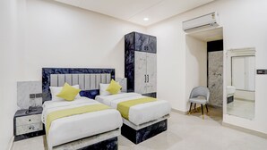 A modern bedroom with two beds, a wardrobe, an air conditioning unit, and a mirror. - The Byke Boutique Tejjora (Lucknow)