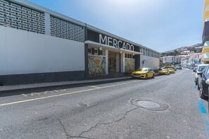 Eine Straße mit einem Gebäude, auf dem 'MERCADO' steht, und gelben Taxis, die am Straßenrand geparkt sind.