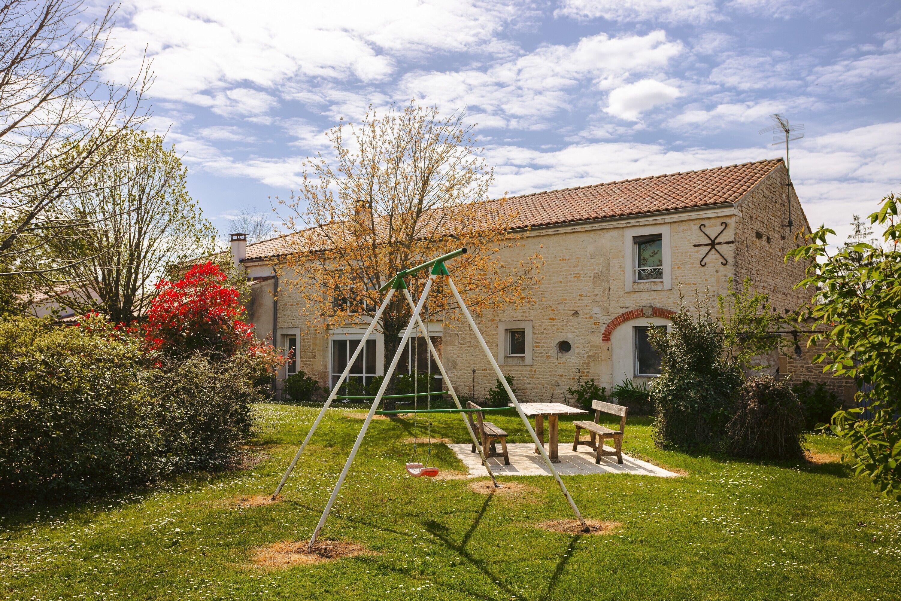 Une maison avec une balançoire, une table de pique-nique et une façade en briques.