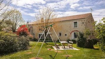 Une maison avec une balançoire, une table de pique-nique et une façade en briques.
