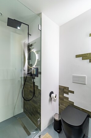 Un baño moderno con ducha de vidrio, inodoro y lavamanos.