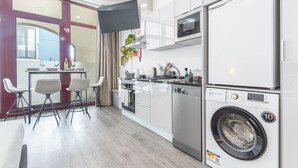 A modern kitchen with a built-in washer and dryer, a dining area with chairs, and a large window. - Santa Cruz Studio 2 by Atlantic Holiday (Santa Cruz)