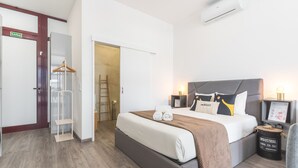 A hotel room with a bed, bedside tables, a wardrobe, a mirror, and an air conditioning unit. - Santa Cruz Studio 2 by Atlantic Holiday (Santa Cruz)