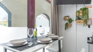 A dining area with a table set for four, a bottle of Gazella wine, and a view of an archway. - Santa Cruz Studio 2 by Atlantic Holiday (Santa Cruz)