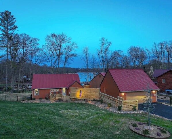 A row of cabins with red roofs, a wooden deck, and a flag. - 2BR 2BA Lakefront Gem – Decks, Docks & Sunsets (Johnson City)