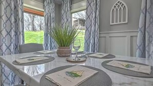 Een eettafel gedekt met placemats, een potplant en een wijnglas.