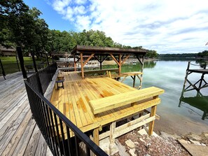 A wooden deck with tables and benches overlooking a calm lake. - 2BR 2BA Lakefront Gem – Decks, Docks & Sunsets (Johnson City)