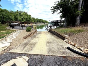 Une jetée en béton menant à un lac paisible, entouré d’arbres et agrémenté d’un espace de pique-nique.