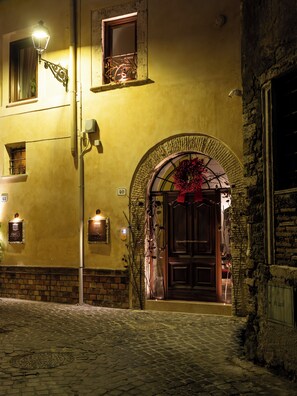 A historic building with a cobblestone street entrance, a large wooden door, and a decorative archway. - Locanda Sibilla Luxury Suites (Tivoli)