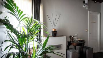 Une pièce avec une grande plante en pot, une table avec un vase et une porte avec une pancarte.
