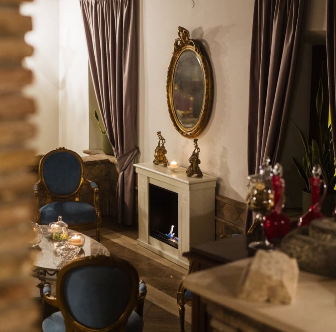 Un comedor con chimenea, un espejo y una mesa dispuesta con velas y adornos.