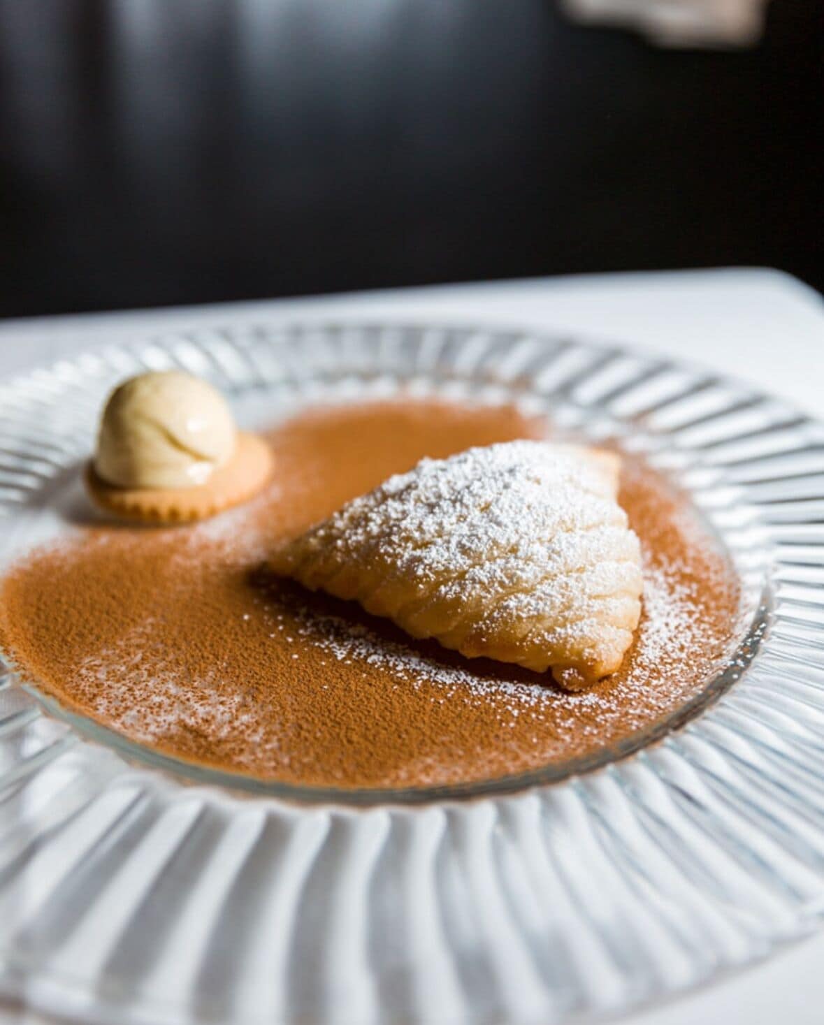 A dessert plate with a pastry dusted with powdered sugar and a scoop of ice cream.