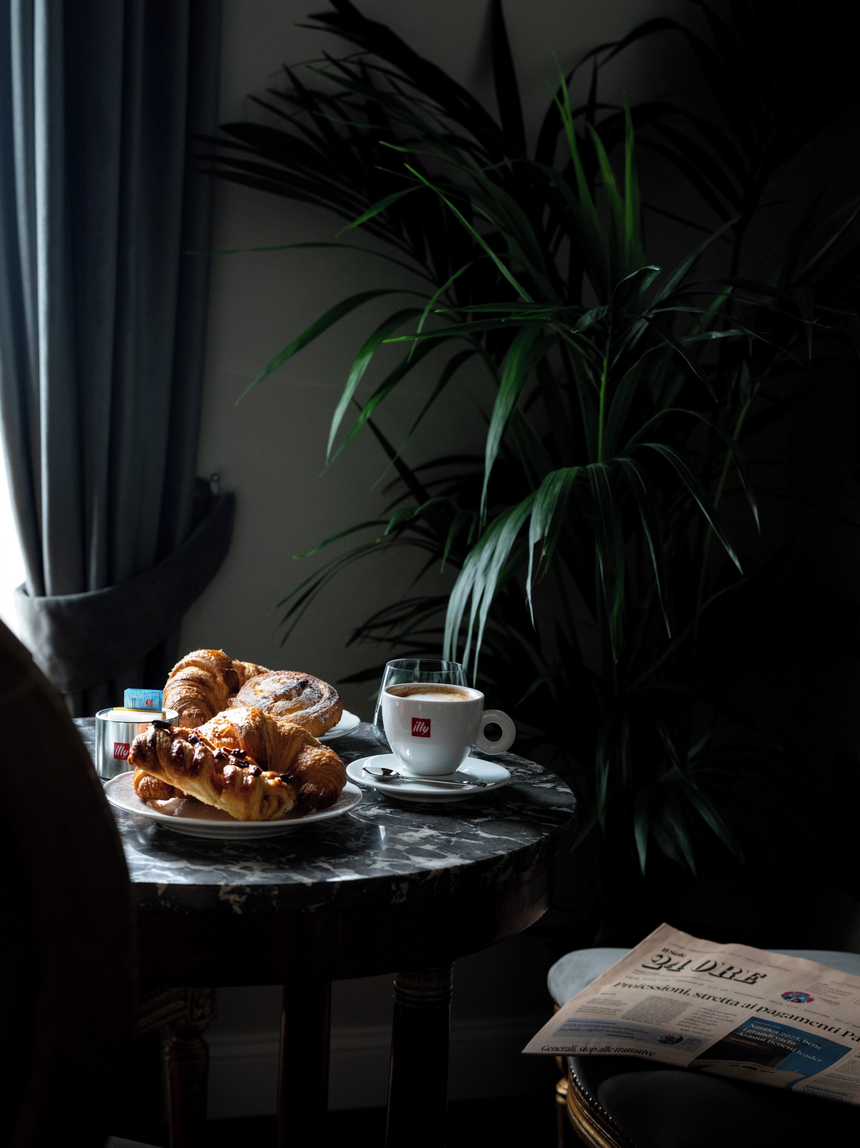 A table with croissants, a cup of coffee, and a newspaper.