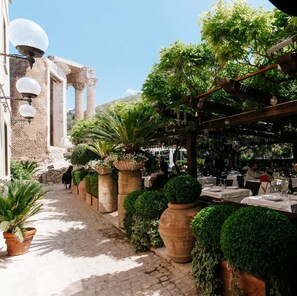 A courtyard with outdoor seating, potted plants, and classical architecture. - Locanda Sibilla Luxury Suites (Tivoli)