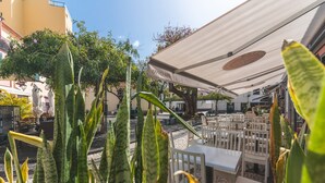 An outdoor seating area with tables and chairs, surrounded by plants and a building in the background. - Santa Cruz Studio 3 by Atlantic Holiday (Santa Cruz)