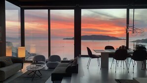 A modern living room with a large window overlooking a sunset view. - Spacious 5-bedroom penthouse in gorgeous Rafailovići - Budva (Rafailovići)