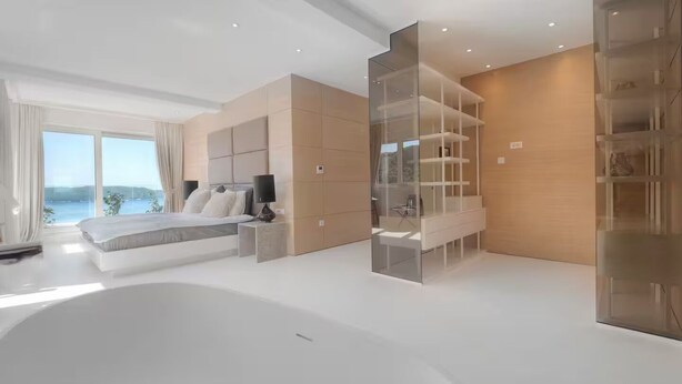 A modern bedroom with a large bed, built-in shelving, and a view of the outdoors. - Spacious 5-bedroom penthouse in gorgeous Rafailovići - Budva (Rafailovići)