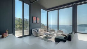 A modern living room with large windows, a sofa, a coffee table, and a rug. - Spacious 5-bedroom penthouse in gorgeous Rafailovići - Budva (Rafailovići)