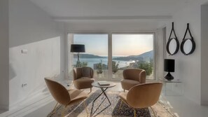 Una sala de estar moderna con un ventanal grande, dos sillones, una mesita y una lámpara.
