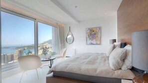 A modern hotel room with a large bed, a round mirror, a painting, and a view of the city and sea. - 1,000 m² Penthouse Retreat in Rafailovići, Budva (Rafailovići)