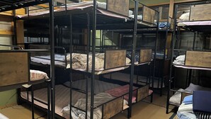 A dormitory room with bunk beds, a small table, and a window. - Echigo-Tsumari Art Triennale near the ski resort. (Tokamachi)