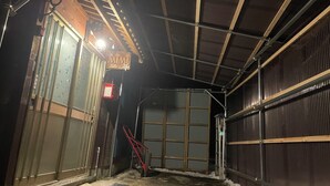 A covered outdoor area with a metal roof, a staircase, and a red bicycle leaning against the wall. - Echigo-Tsumari Art Triennale near the ski resort. (Tokamachi)