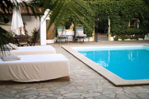 A poolside area with two white lounge chairs, a table, and a bench. - Monte dos 2 Tanques (Estremoz)