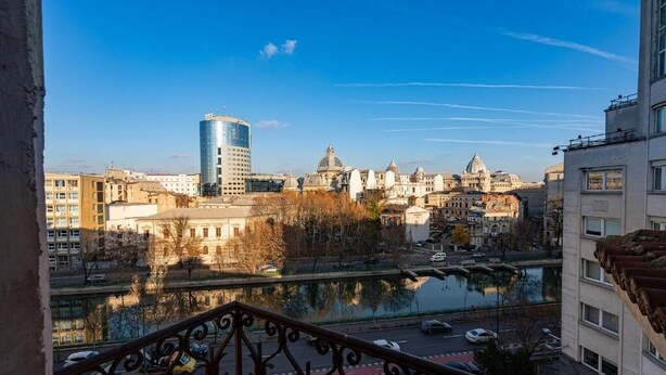 A cityscape with a river, buildings, and a clear sky. - Golden Hour Residence - Elegant Cityview Apartment in Historic Bucharest (București)