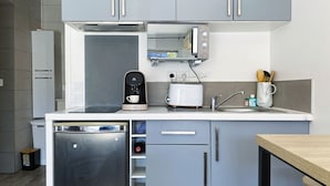 Et kompakt køkken med kaffemaskine, brødrister og opvaskemaskine.