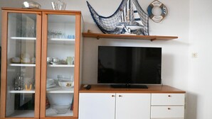 Eine Küche mit Fernseher, einem Holzschrank und einem Regal mit maritimer Dekoration.