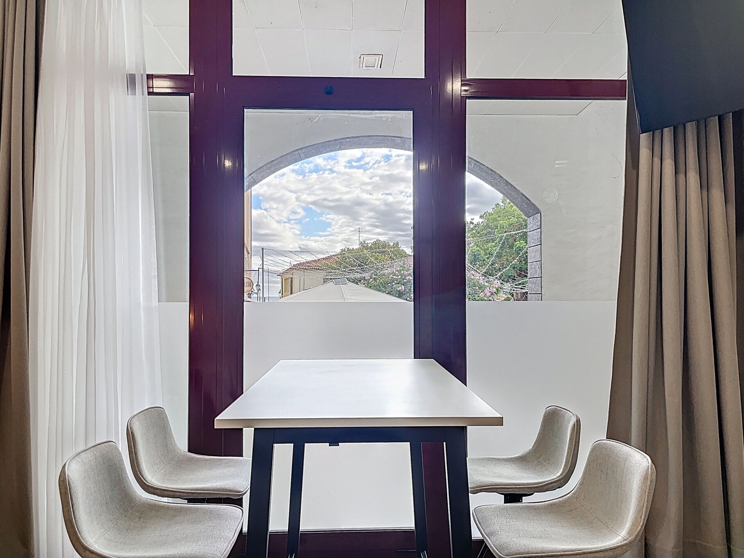 Una habitación con un ventanal amplio, una mesa blanca y dos sillas.