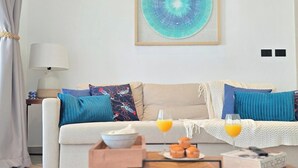Ein Wohnzimmer mit einer Couch, zwei Beistelltischen, einem Couchtisch und einem gerahmten Kunstwerk an der Wand.