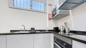 Eine moderne Küche mit schwarzem Arbeitsplatz, Edelstahlgeräten und weißen Schränken.