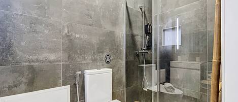 A modern bathroom with a glass-enclosed shower, a toilet, and a sink.