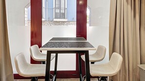 Ein Konferenzraum mit Tisch und vier Stühlen, einem fensterartigen Rotrahmen und Blick auf ein blaues Gebäude.
