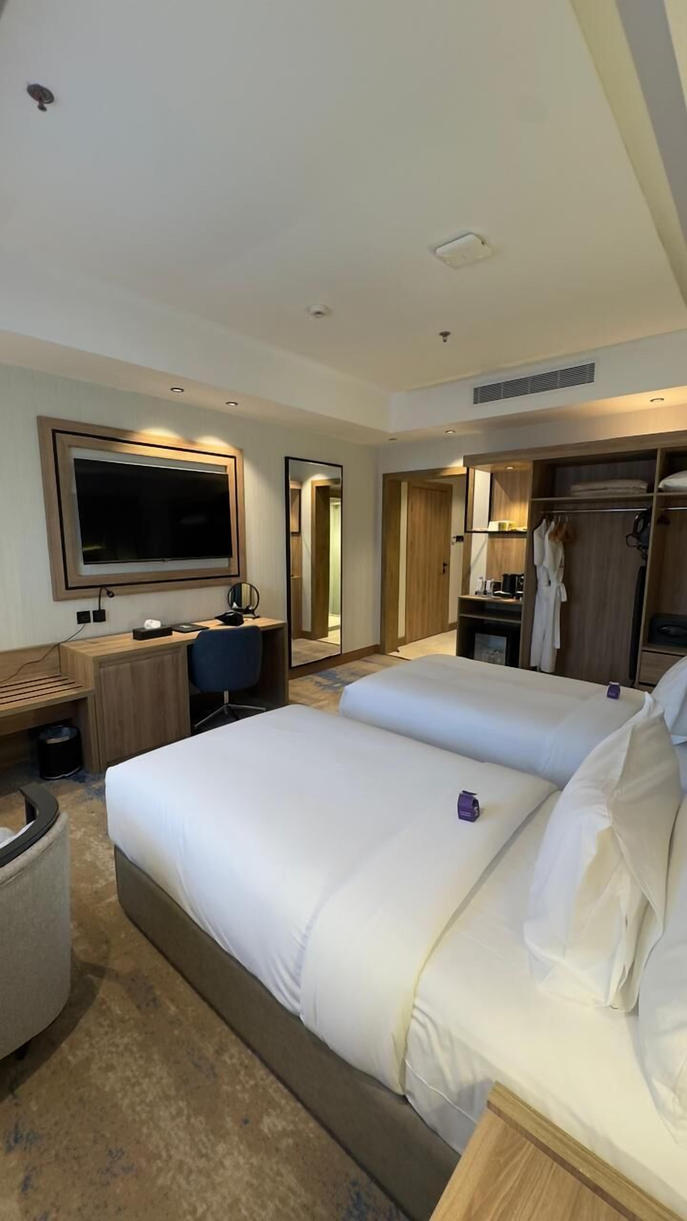 Una habitación de hotel con una cama grande, un escritorio, una silla, un televisor y un armario.