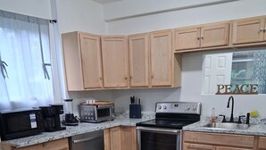 A modern kitchen with wooden cabinets, stainless steel appliances, and a herringbone-patterned floor. - Relax & Recharge: Your Dream Stay in Port Carbon! (Port Carbon)