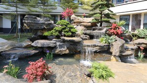Een aangelegde tuin met een kleine waterval, rotsen en diverse planten.