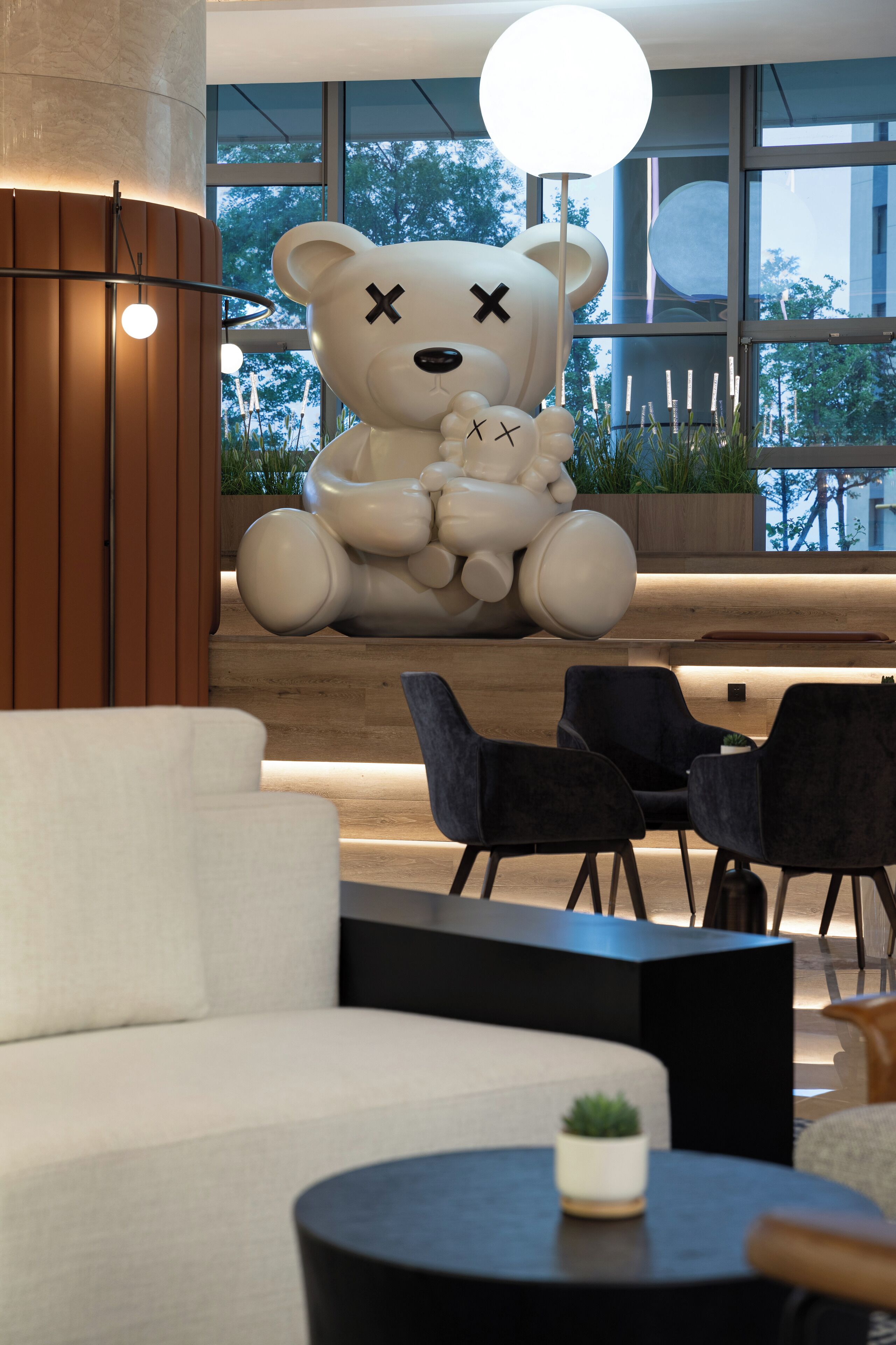 A modern interior with a large white bear sculpture, black chairs, and a white sofa.
