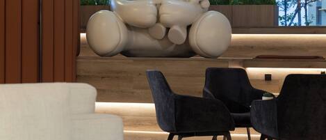 Un interior moderno con una gran escultura de un oso blanco, sillas negras y un sofá blanco.